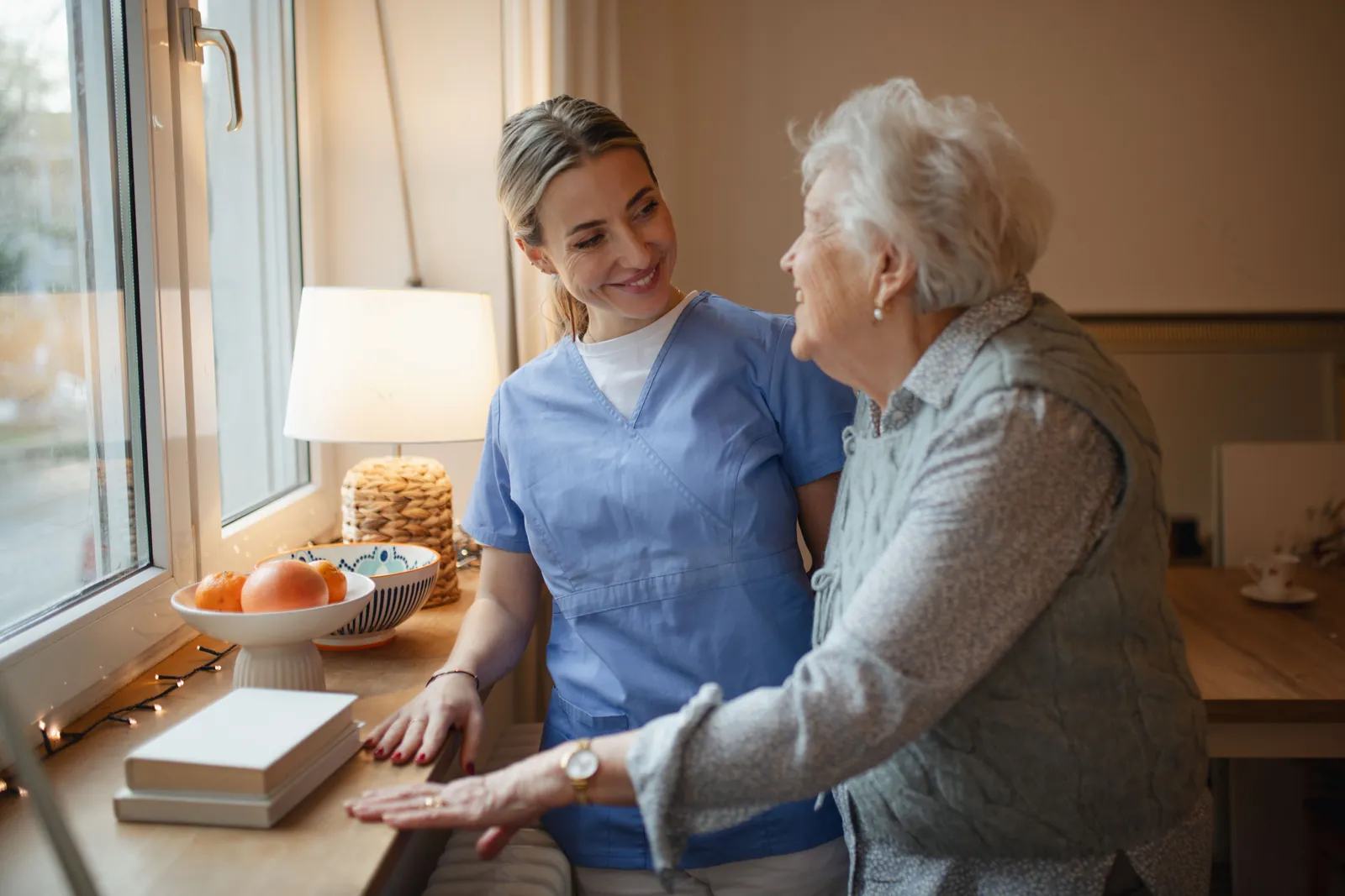 Carer and older woman chatting by the window