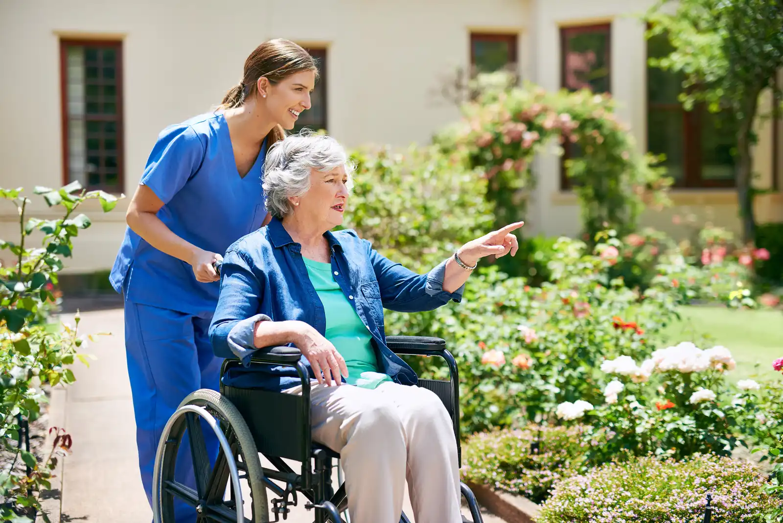 Carer wheeling her client through a summer garden