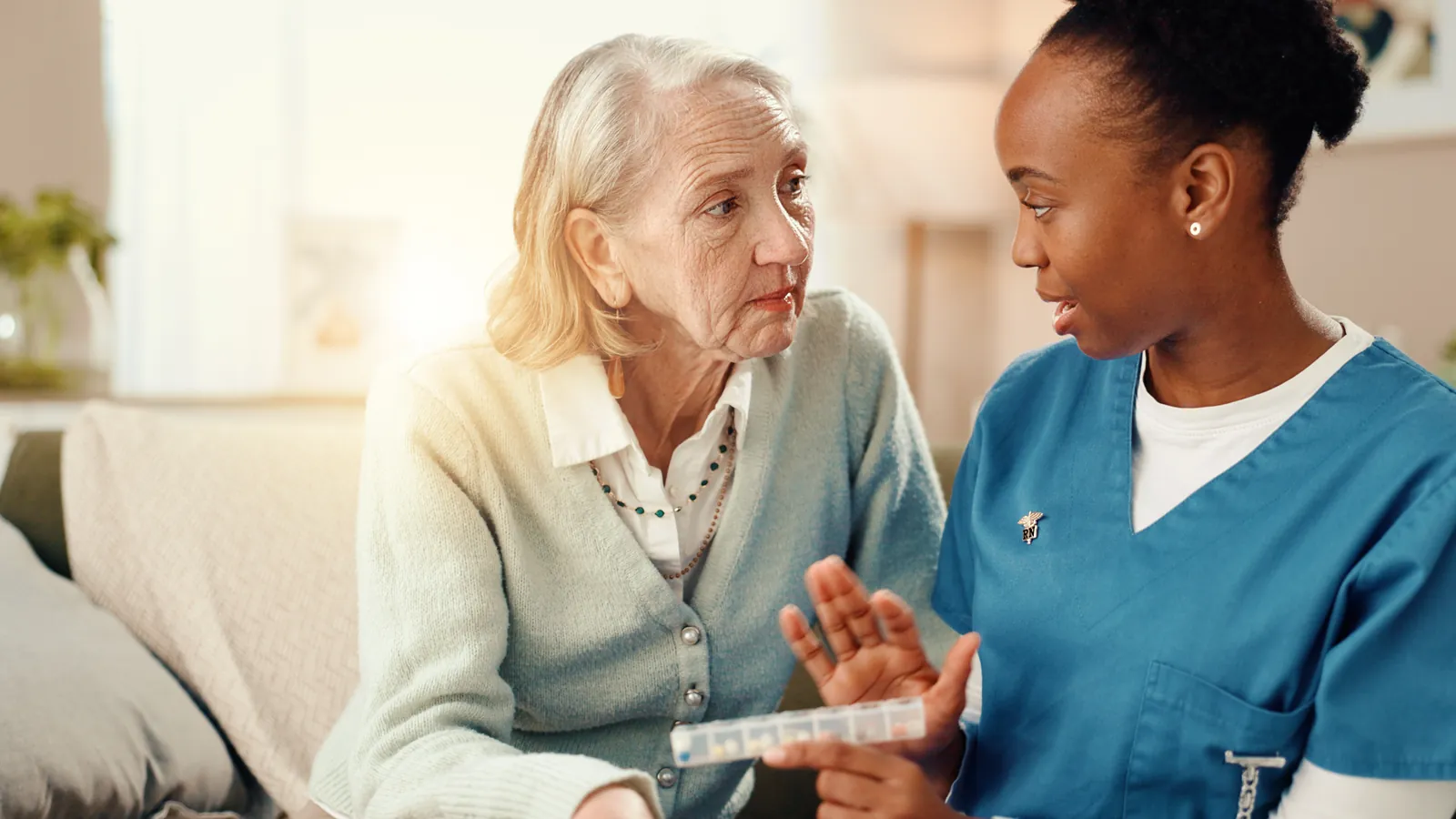 Nurse explaining medication to an older woman at home